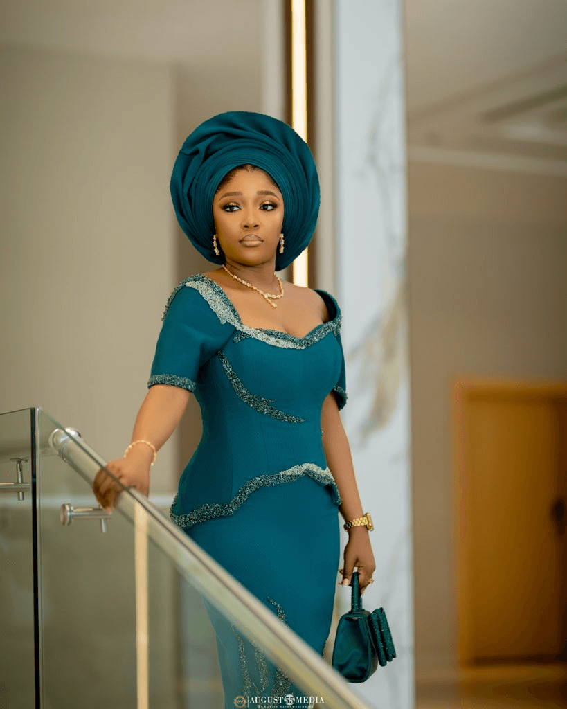 Teal fitted dress with gold trim and matching gele